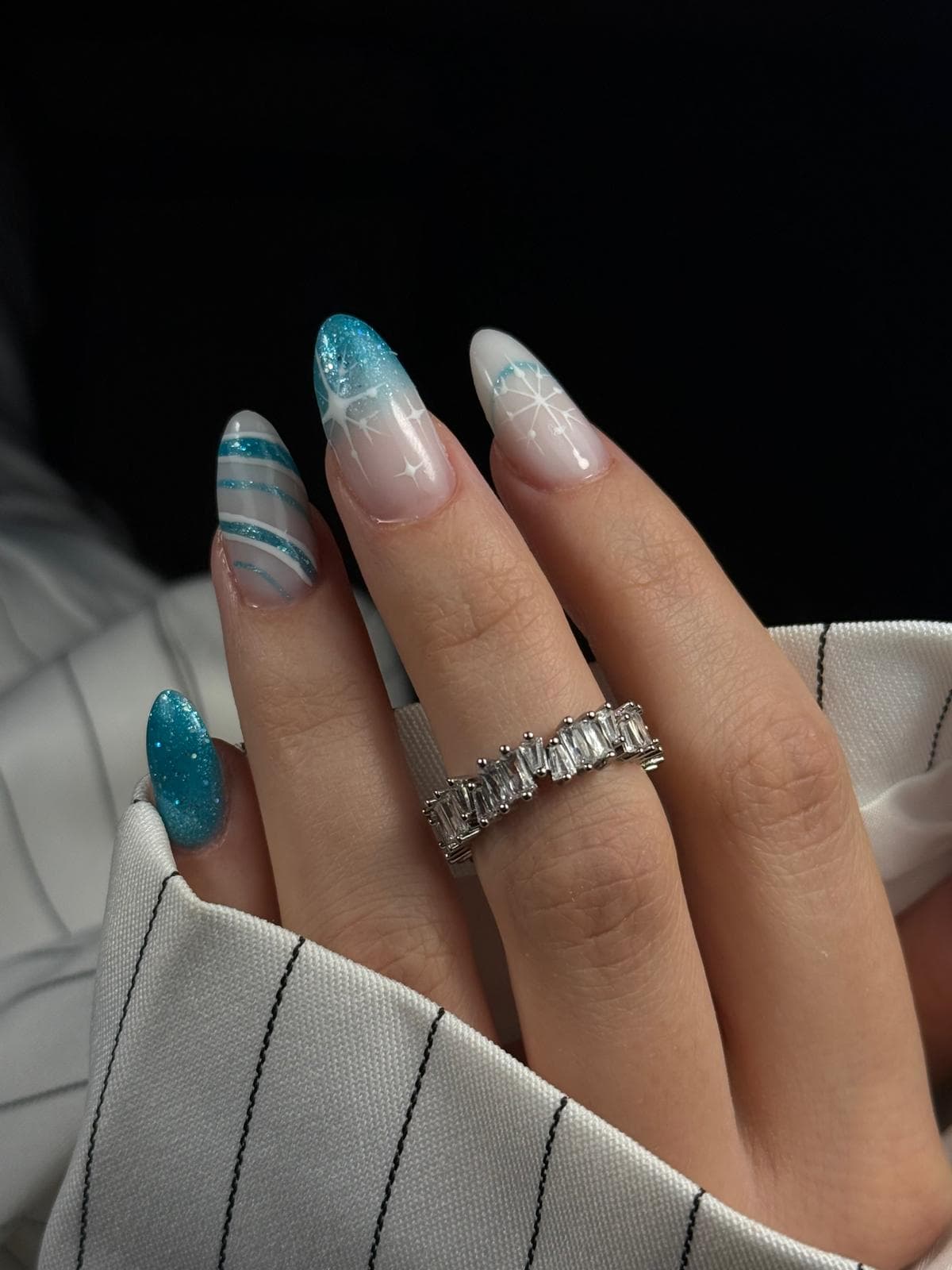 Blaue Glitzer-Nägel mit weißen Stern- und Schneeflockendetails